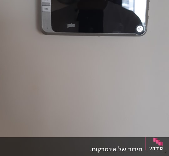 מסך אינטרקום עם כפתורים על קיר לבן
